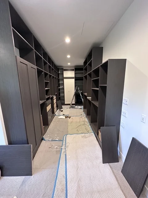 Dark custom cabinetry and shelving in newly renovated walk-in closet with recessed lighting