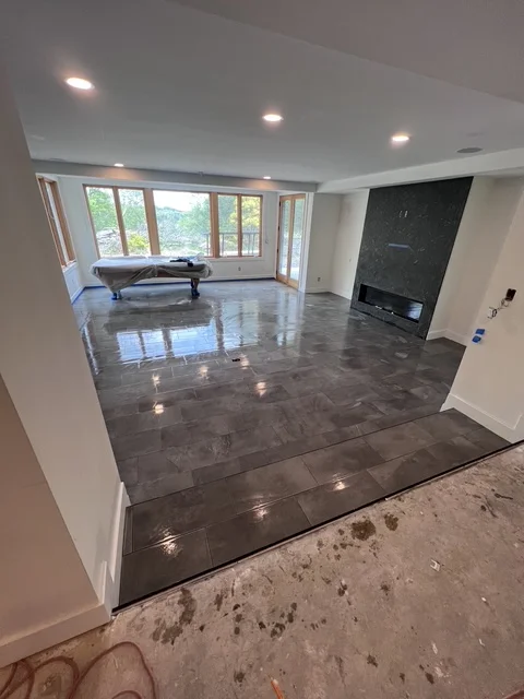 Dark tile flooring in open living room with fireplace and large windows