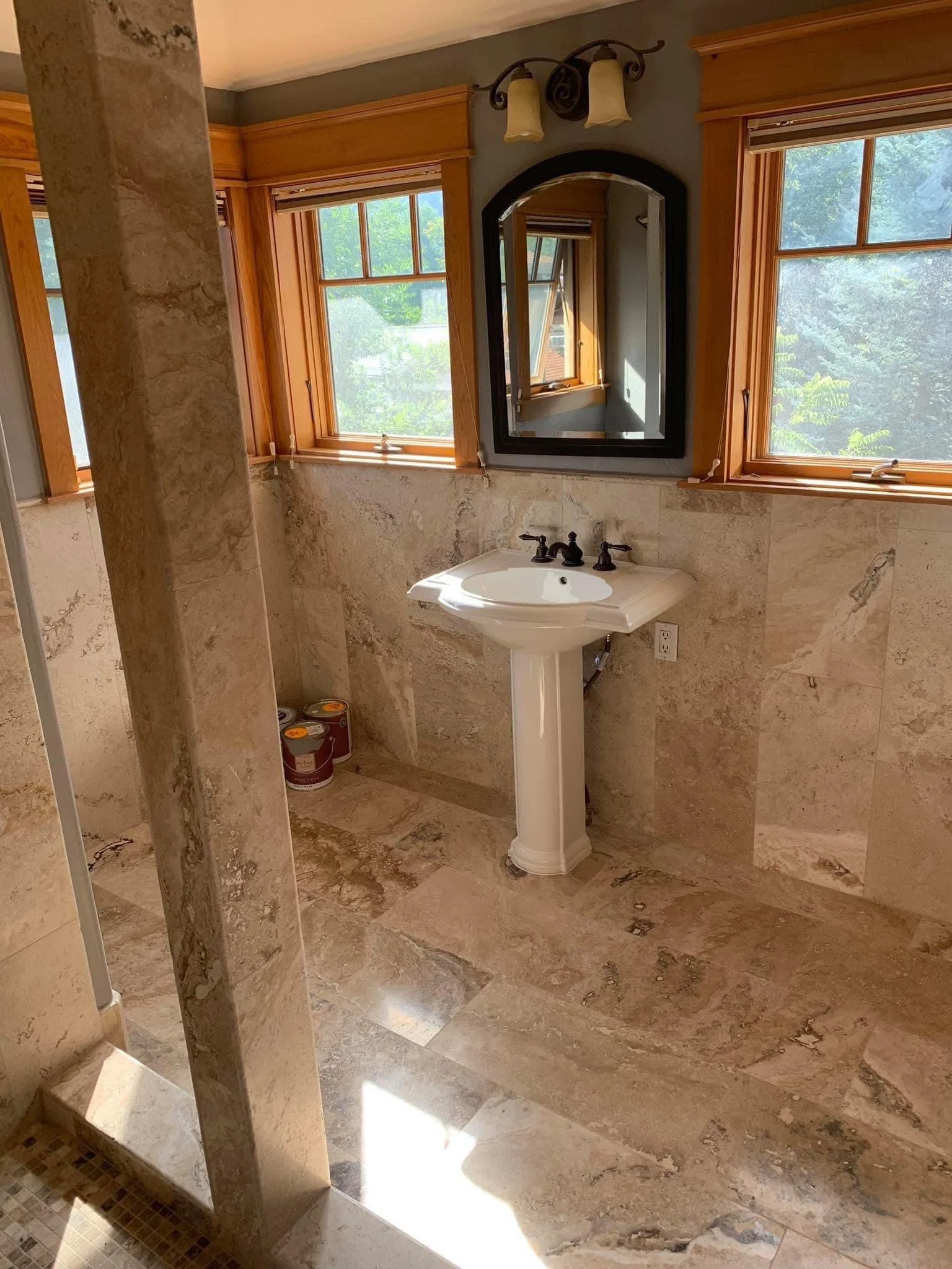 Bathroom with travertine tile walls and flooring, pedestal sink, and walk-in shower