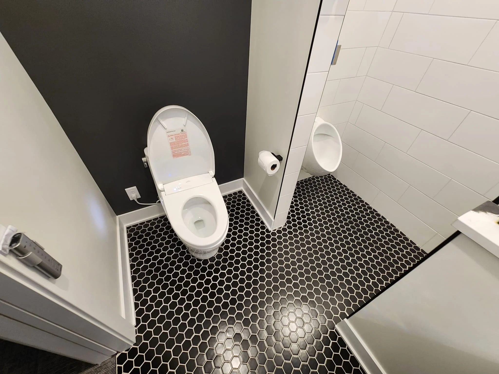 Modern bathroom with black hexagonal floor tiles, white walls, and contemporary fixtures