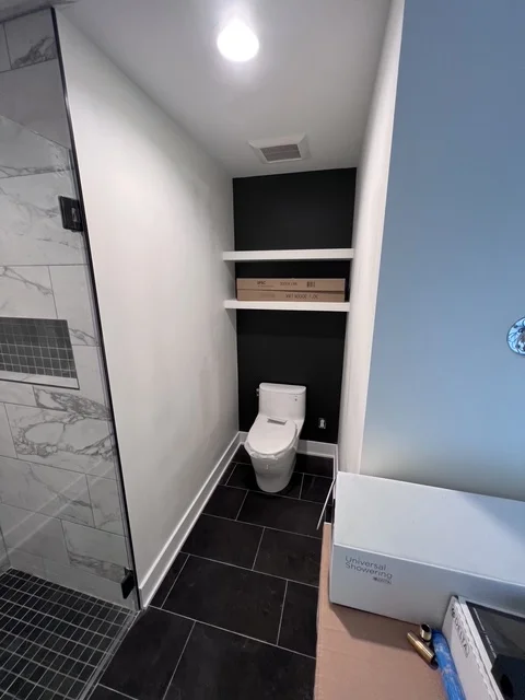 Modern bathroom with black tile floor, white walls, built-in shelving, and contemporary fixtures
