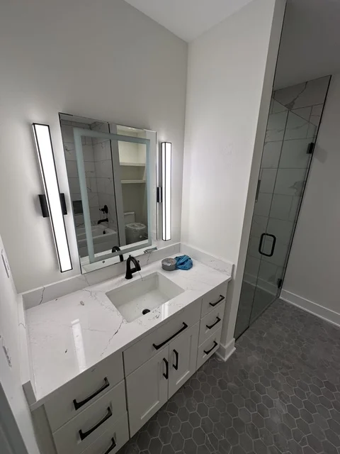 Modern bathroom with white vanity, quartz countertop, and frameless glass shower
