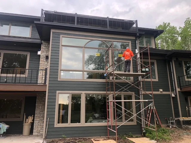 Modern home exterior with gray siding and large multi-pane windows under construction