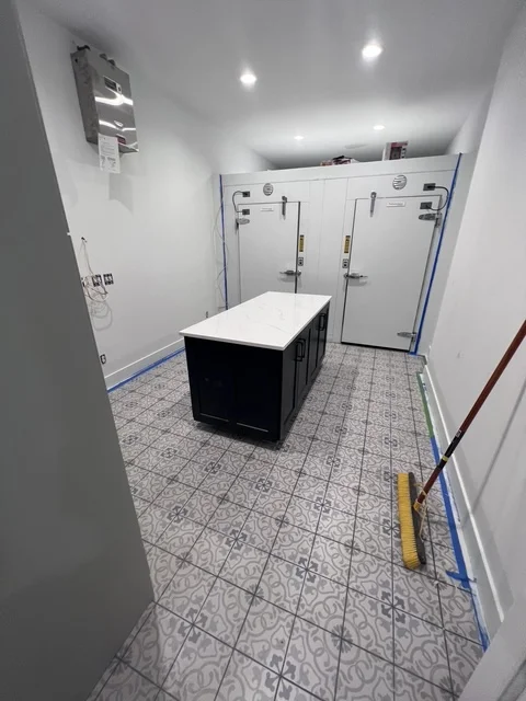 Modern bathroom with black vanity, geometric tile floor, and dual glass shower enclosures