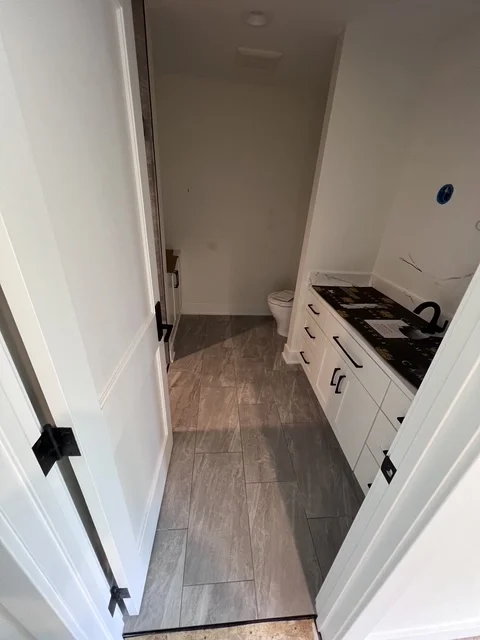 Newly remodeled bathroom with white vanity, black countertop, and wood-look flooring