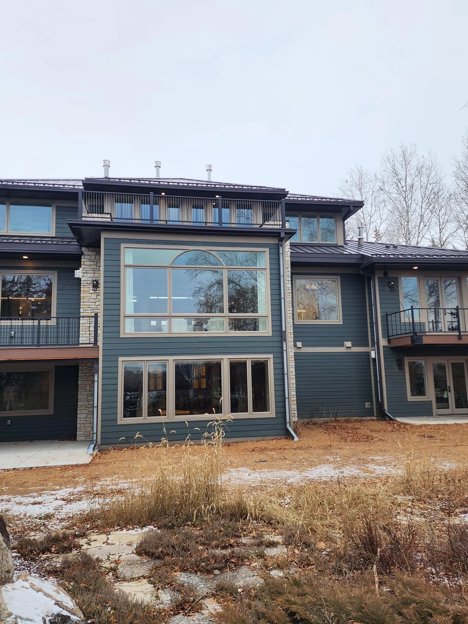 Modern two-story home addition with blue siding, stone accents, and large contemporary windows