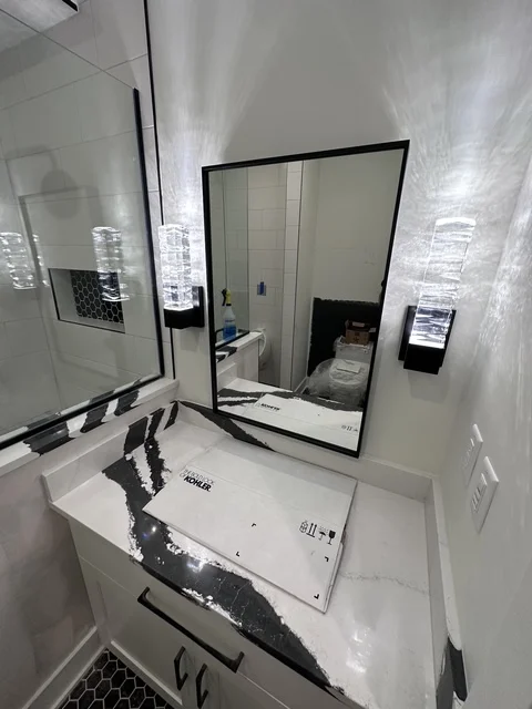 Modern white bathroom vanity with black-framed mirror and hexagonal floor tile