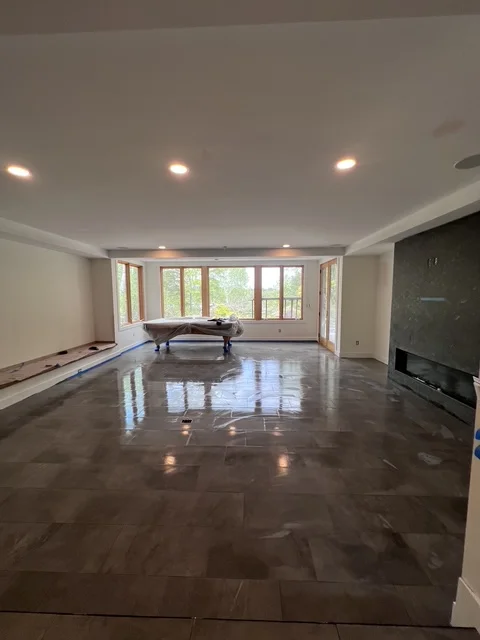 Dark herringbone tile flooring in spacious basement with recessed lighting and large windows