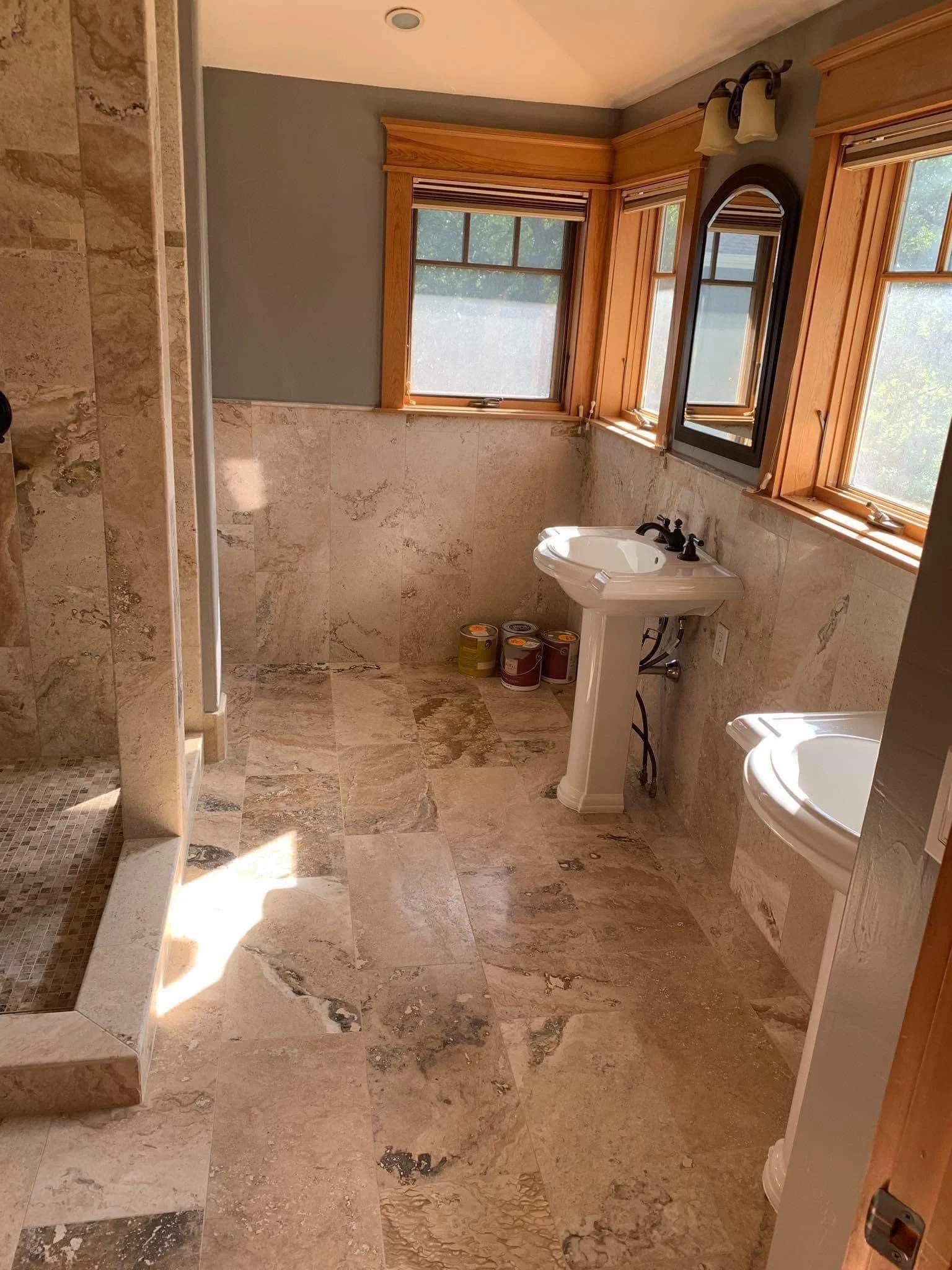 Spacious bathroom with travertine tile flooring, pedestal sink, and walk-in shower