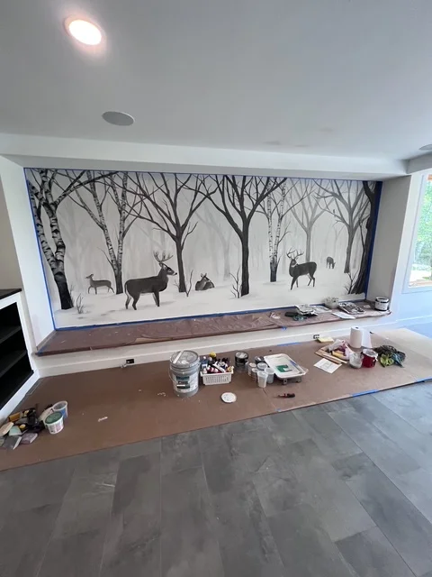Kitchen renovation with forest wildlife mural above brown countertop and white cabinetry
