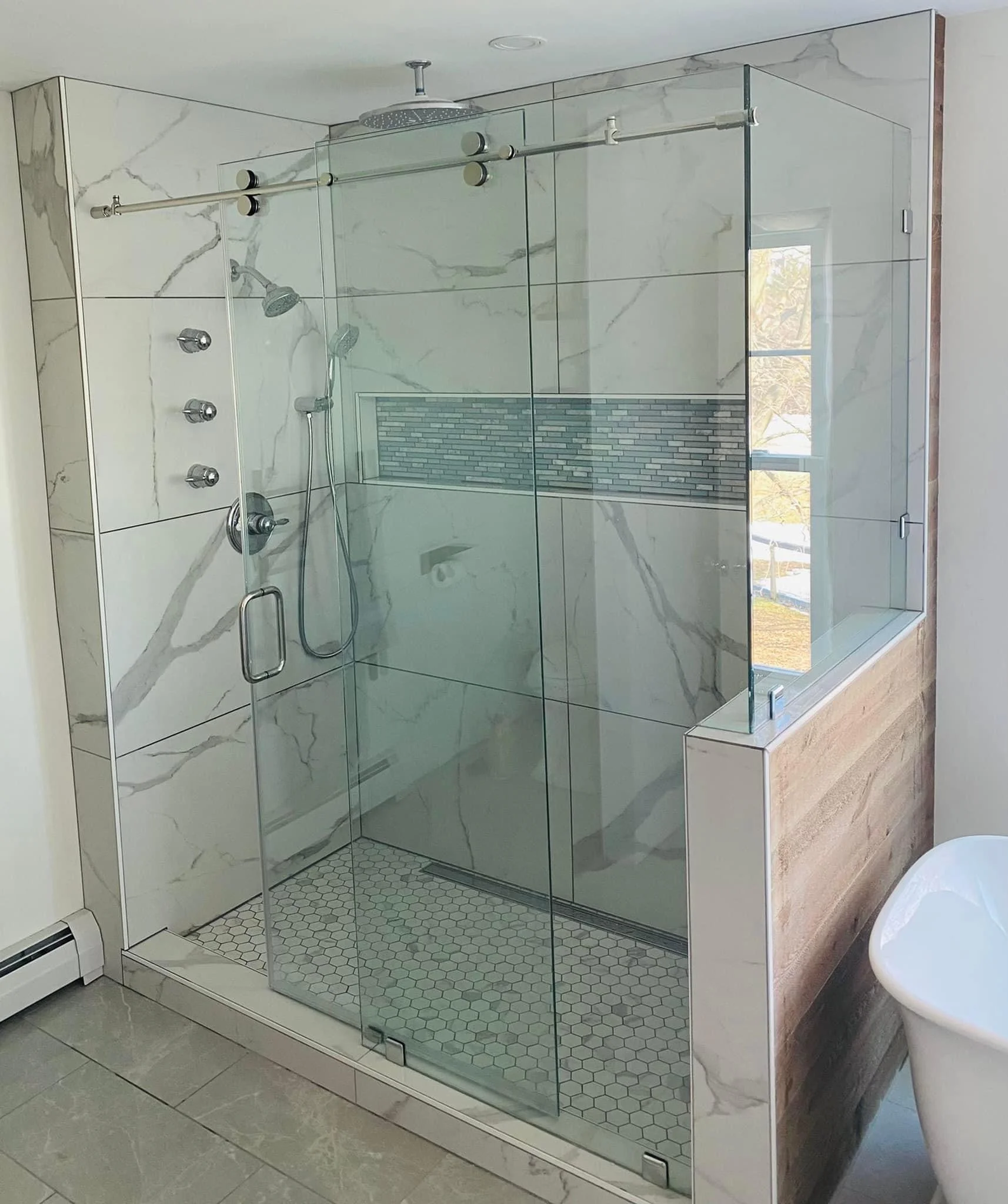Frameless glass shower with marble tile, green accent band, and dual showerheads