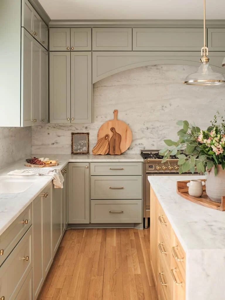Modern farmhouse kitchen with sage green cabinets, marble counters, and hardwood floors