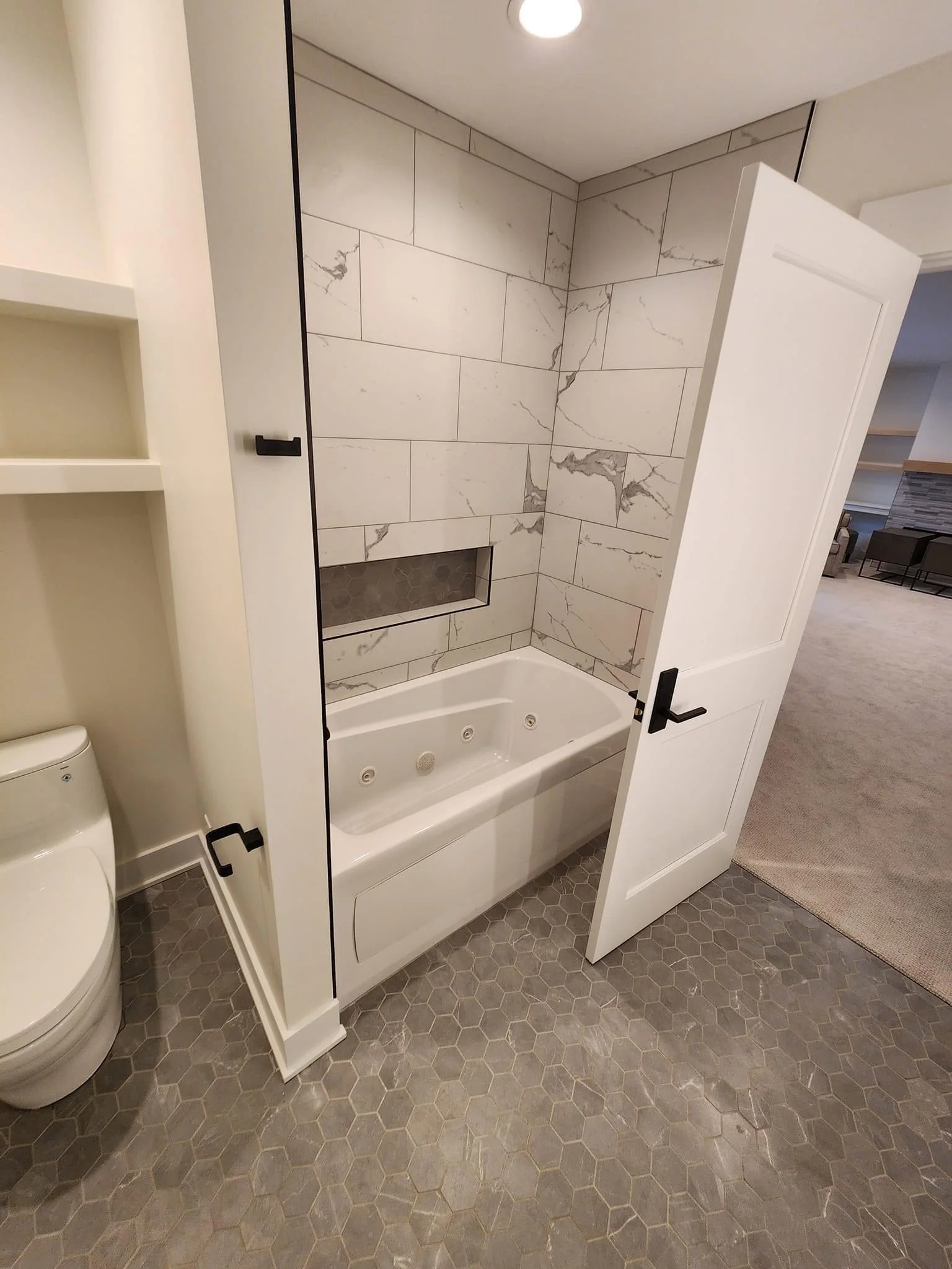 Modern bathroom with frameless glass shower, marble tile walls, and whirlpool tub