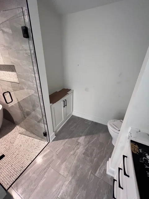 Modern bathroom with gray tile flooring, white subway tile shower, and white vanity
