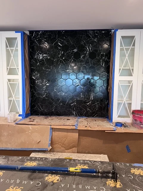 Kitchen remodeling in progress with protective coverings and white cabinetry
