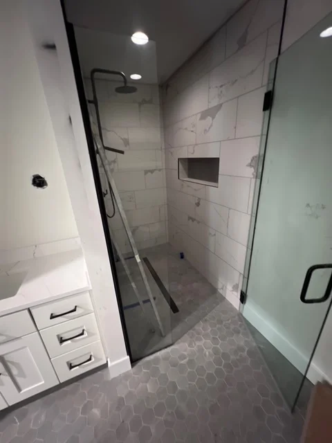 Modern bathroom with white subway tile shower, hexagonal floor tiles, and frameless glass enclosure
