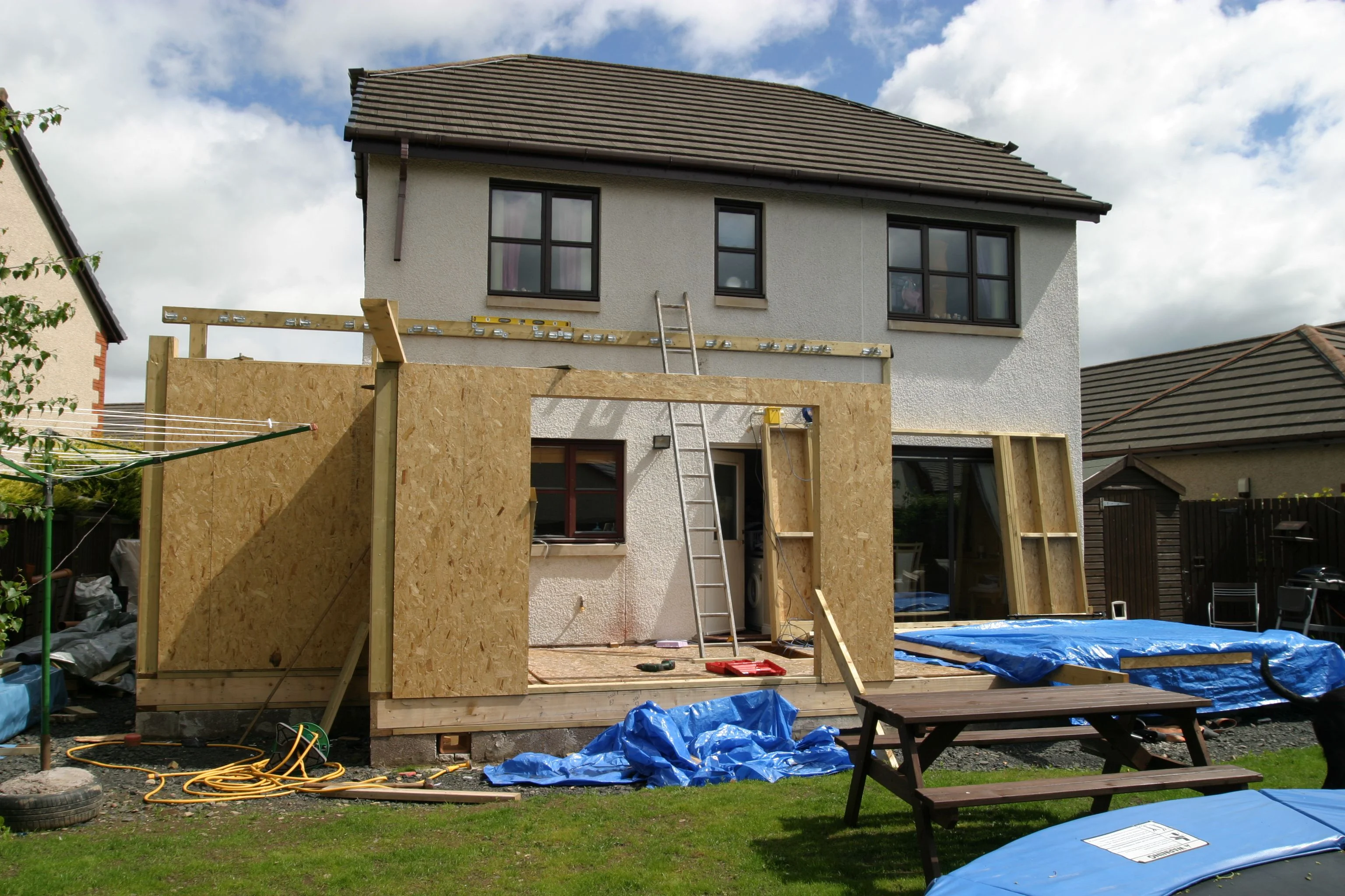 Home addition framing with OSB sheathing, lumber frame, and concrete foundation during construction