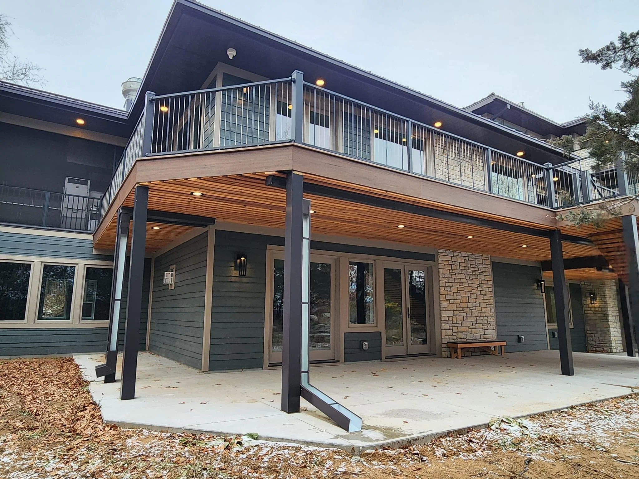 Modern home addition with covered patio, composite deck, and second-story railing