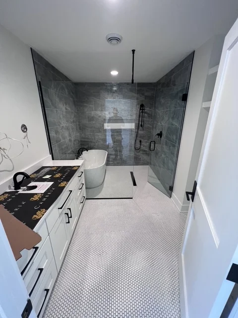 Modern bathroom with gray tile shower, white vanity, and hexagonal floor tile
