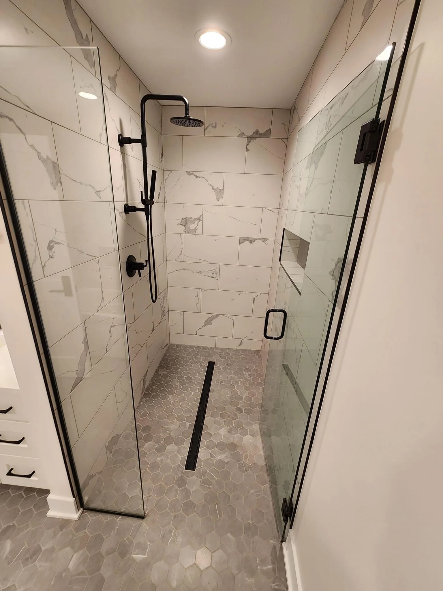 Modern bathroom shower with marble subway tile walls and hexagonal floor tile